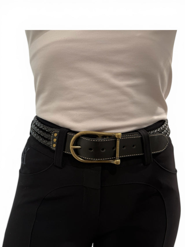 Person wearing a beige shirt, black pants, and a decorative belt with a gold buckle on a white background