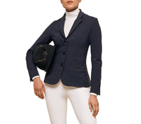 Person wearing a navy equestrian jacket with white pants on a white background