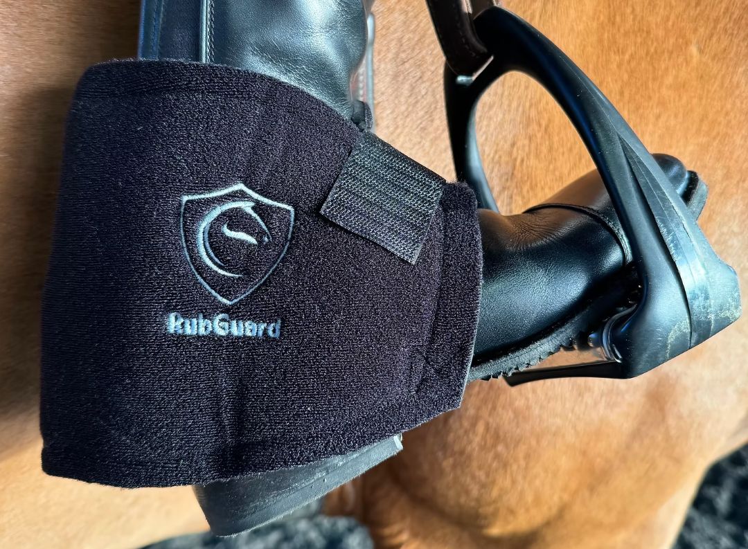Black 'RubGuard' protective pad on a horse's leg with a wooden floor background