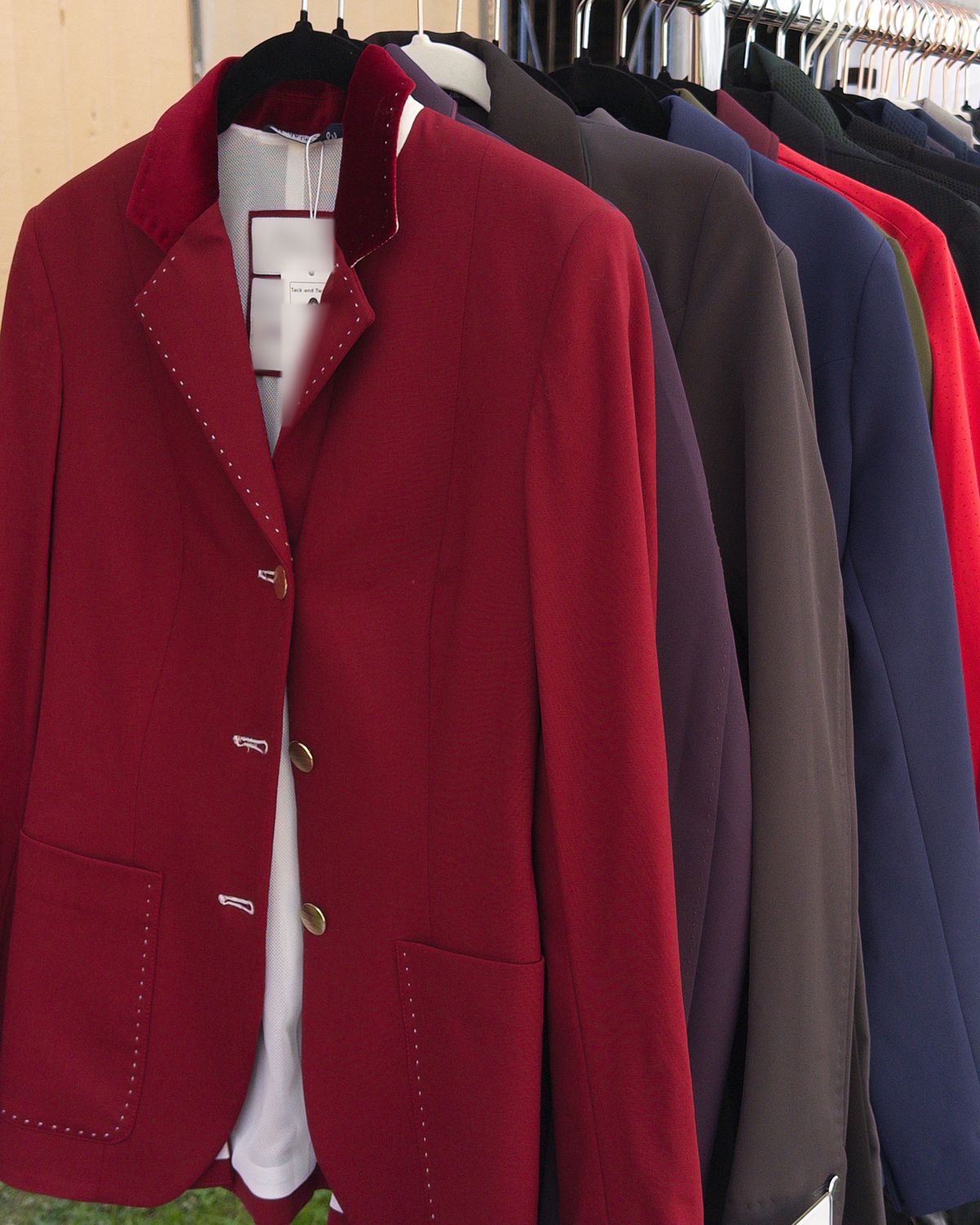 A rack of consigned show coats with a red coat in front.