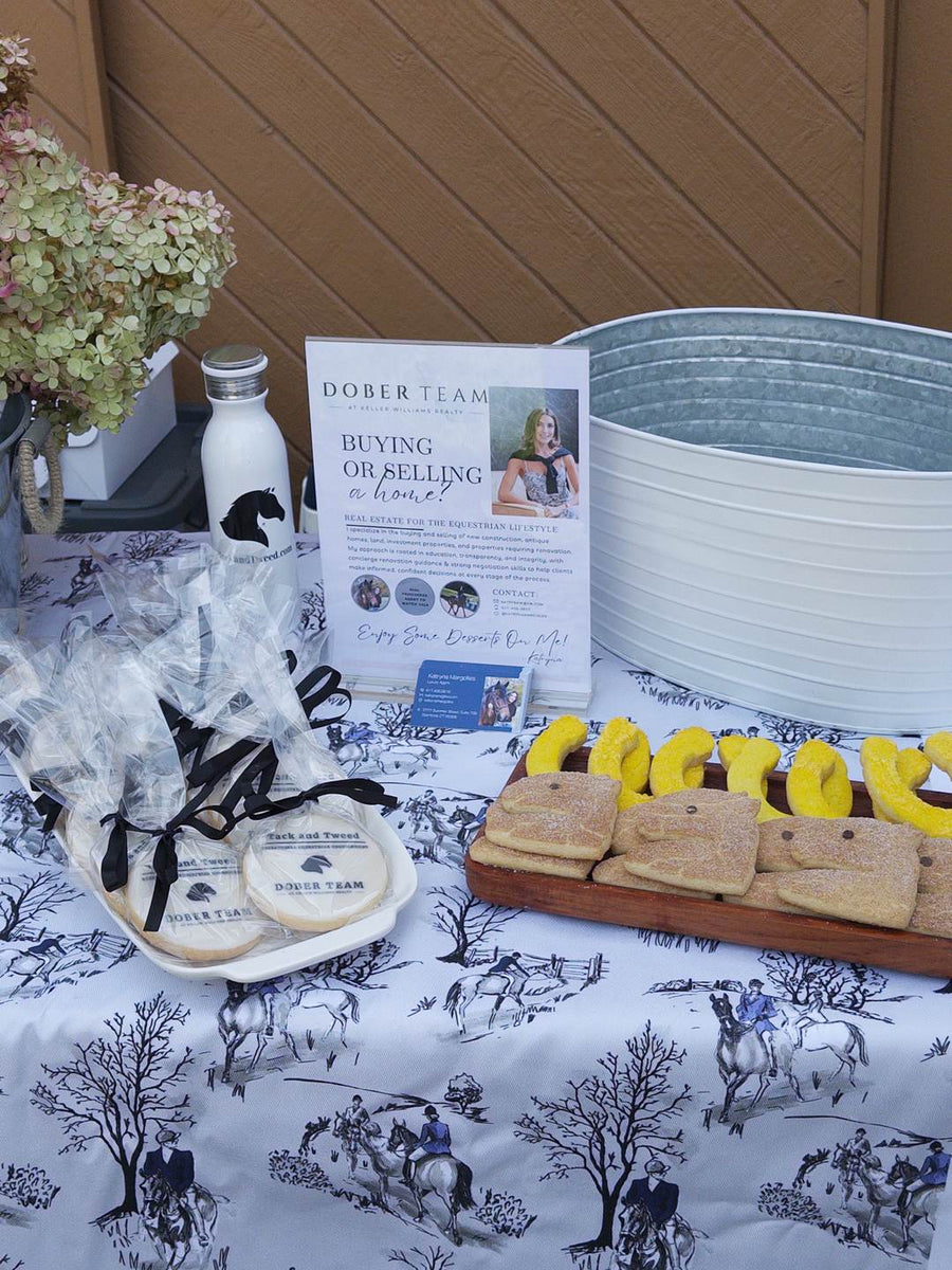 Tack and Tweed table in the hospitality tent with wrapped treats, flowers and a framed sign.