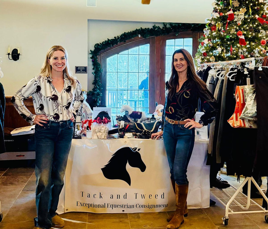 Two Tack and Tweed hosts at their booth with racks of riding apparel and a Christmas tree.
